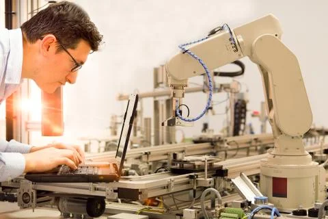 Engineer is working on laptop to programming smart factory automation Stock Photos