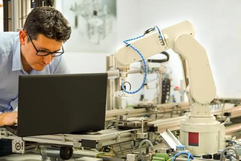 Engineer is working on laptop to programming smart factory automation Stock Photos