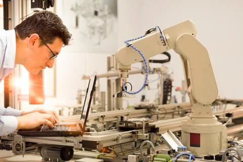 Engineer is working on laptop to programming smart factory automation Stock Photos