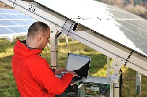 Engineer working with laptop by solar panels Stock Photos