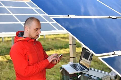 Engineer working with laptop by solar panels, talking on cell phone Stock Photos