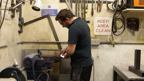 Engineer working on Linishers Belt Grinders in a tidy workshop with a KEEP Stock Footage 271233107