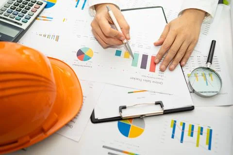 Engineer working project accounting with graph and construction helmet in o.. Stockfoto's