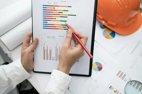 Engineer working project accounting with graph and construction helmet in o.. Stockfoto's