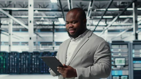 Engineer working in server farm using tablet to analyze data Stock Footage 311896892