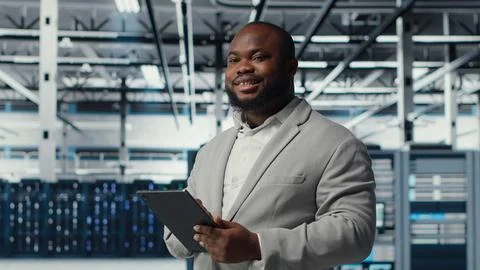 Engineer working in server farm using tablet to analyze data Stock Photos
