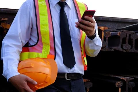 The engineer is working with smart phone with large industry background. Stock Photos