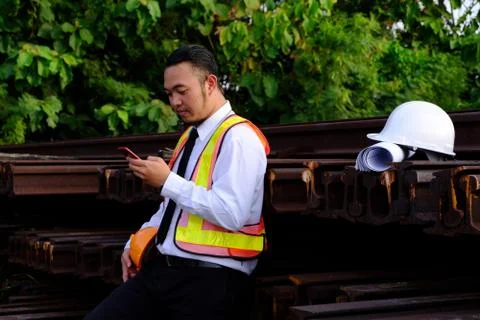 The engineer is working with smart phone with large industry background. Stock Photos