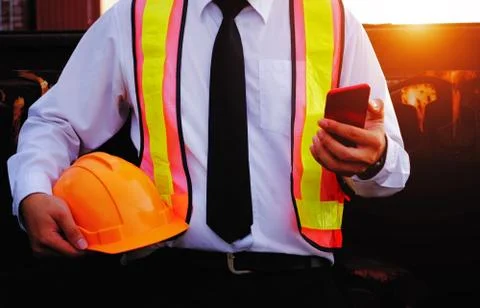 The engineer is working with smart phone with large industry background. Stock Photos