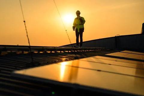 Engineer working at solar cell farm power plant with sunset in evening Stock Photos