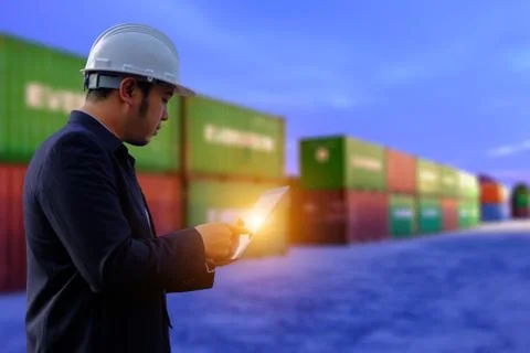 The engineer is working with tabet on containers background. Stock Photos