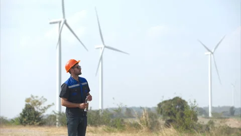 Engineer working in wind turbine farm with blue sky background Stock Footage 264134259