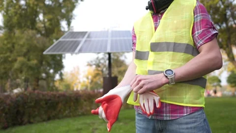 Engineer on workplace puts on protective gloves while standing in front of solar Stock Footage 290993312