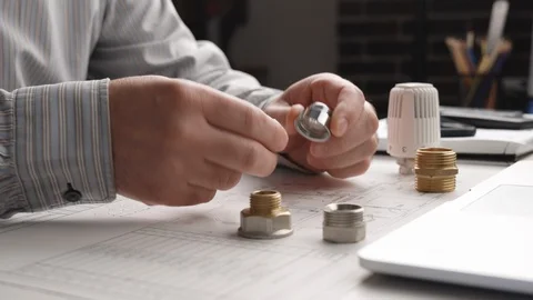 Engineer works and assembling plumbing elements and drawings are on the desktop. Video stock 129260385