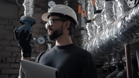 Engineer works in boiler room, dictates audio message on smartphone Stock Footage