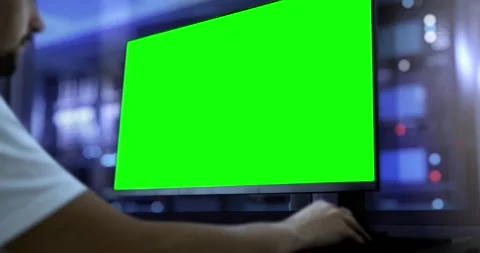 An engineer works on a computer with a green screen. In the background, the.. Stock Footage 246048538
