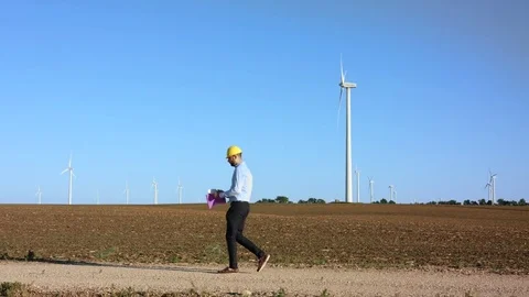 The engineer works with the drawings against the background of windmills Video stock 76583853
