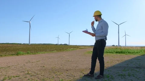 The engineer works with the drawings against the background of windmills Video stock 76589293
