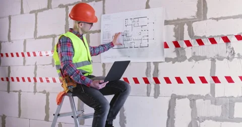 Engineer works with laptop analyzing floor plan of apartment Stockbeeldmateriaal 309927607