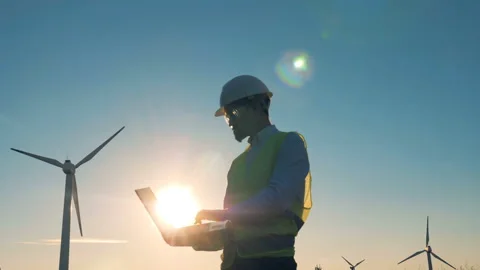 Engineer works on a sunset background. Windmills, green energy concept. Stock Footage