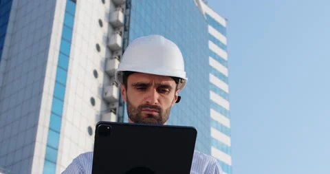 Engineer works via tablet standing against highrise building Stockbeeldmateriaal 166055114