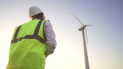 Engineer in a yellow vest and a white helmet suitable to the windmill to check Stock Footage 112018758