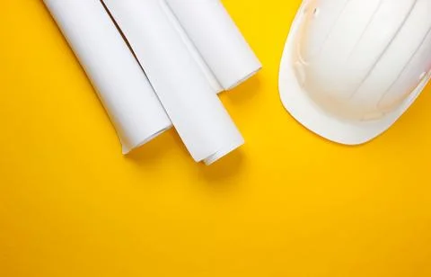Engineering construction safety helmet, drawing rolls on yellow background. B Stockfoto's