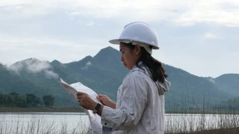 Engineering holding a riverbank map to develop a hydroelectric dam. Vídeos de archivo 204402460