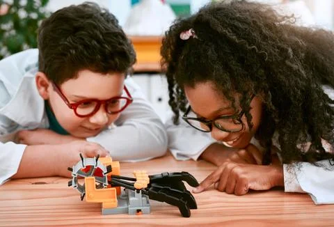 Engineering, learning and children building a robot hand together in a classroom Stock Photos