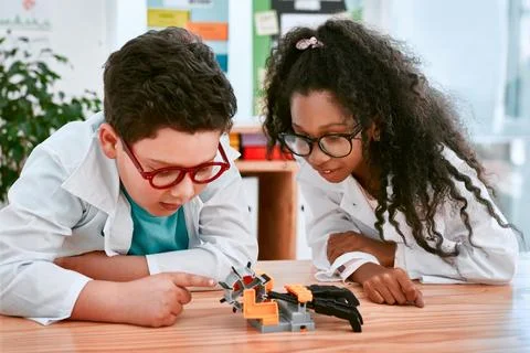 Engineering, learning and children building a robot hand together in a classroom Stock Photos