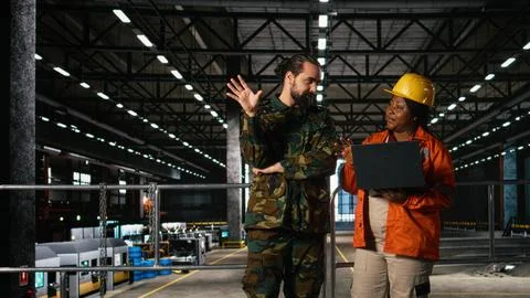 Engineering specialist and armed forces officer inspect heavy machinery Stock Photos