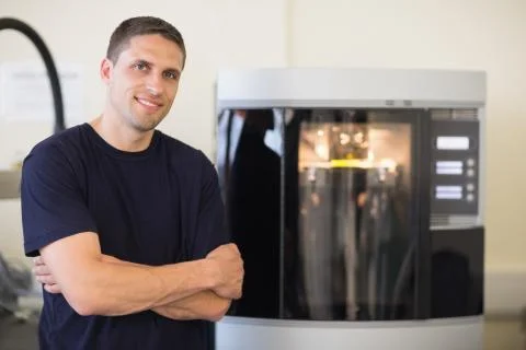 Engineering student smiling beside 3d printer Stock Photos