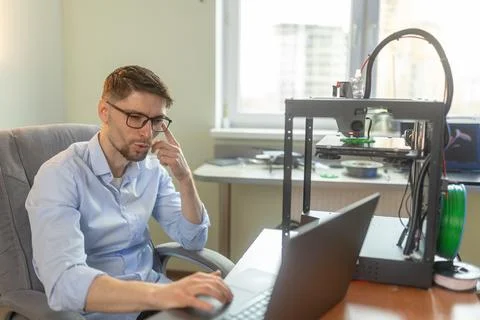 Engineering student working in the lab with a laptop, 3D printer in the Stock Photos