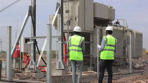 Engineering team conducting an on-site audit of a large electrical transformer Stock Footage 336394166