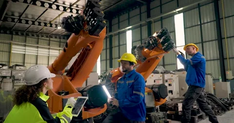 Engineering team inspects industrial robotic arms in factory workshop Stock Footage 341683683