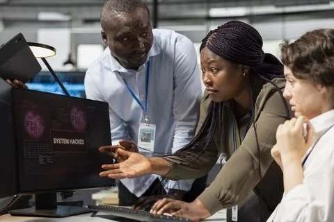 Engineering team in office working together to fix hacking attempt 库存照片