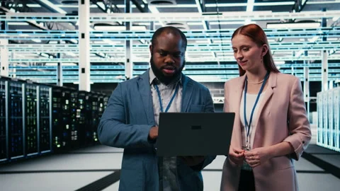 Engineering team in server hub working together with laptop to do maintenance Stock Footage 330139573