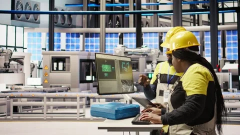 Engineering team using PC in smart factory to oversee robotic assembly lines Video stock 308726734