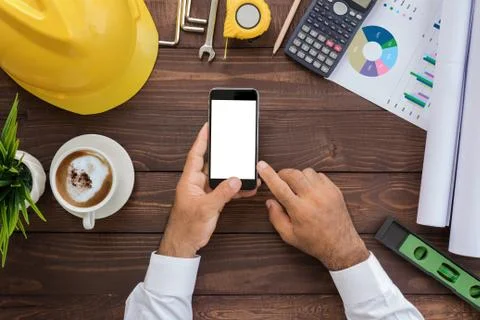 Engineering using phone on his workspace top view Stock Photos