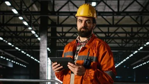 Engineering worker overseeing heavy industry production line with tablet 스톡 사진