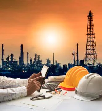 Engineering working on computer tablet against silhouette of oil refinery pla Stock Photos