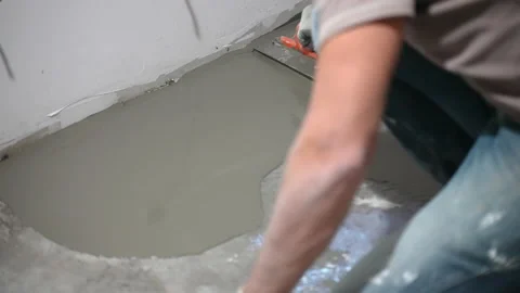 Engineering workman pouring self-leveling screed on floor, spreading it and Stock Footage 148888935