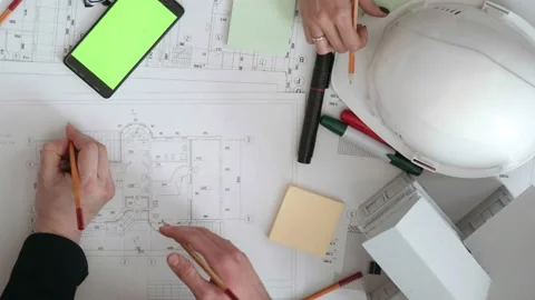Engineers actively amend pencils on a large drawing of the house lying on the Stock Footage 103038686
