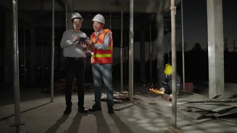 Engineers and architects are consulting on a construction site with workers Stock Footage 169764296