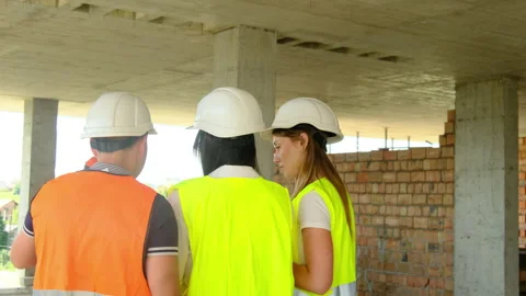Engineers and builder consult against brick wall in building Stock Footage 317617274