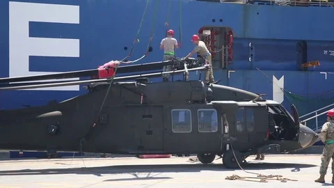 Engineers attaching lifting gear to helicopter for loading onto ship  Stock Footage 90417675