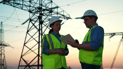 Engineers building high-voltage lines. Business partners working with computer Fotos de archivo