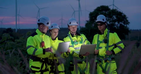 Engineers checking laptop data during dusk wind farm inspection, teamwork Stock Footage 330762010