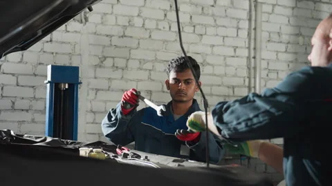 Engineers Collaborate on Car Engine Repair in Auto Workshop 库存影片 302196607