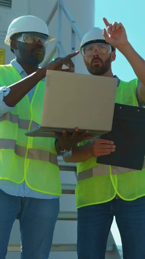 Engineers collaborate on a construction site using a laptop for their tasks and Stock Footage 314206546